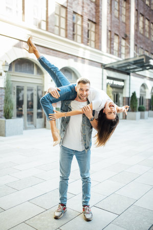 Fashion outdoor romantic portrait of beautiful young couple in love and hugs on the street.の写真素材