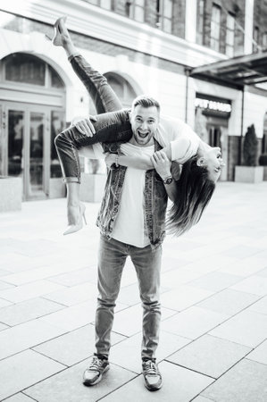 Fashion outdoor romantic portrait of beautiful young couple in love and hugs on the street.の写真素材