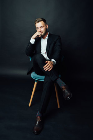 Handsome businessman man sitting on chair in photo studioの写真素材