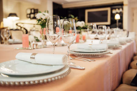 Luxurious restaurant. Luxurious interior, white tables, serving dishes and glasses for guestsの写真素材