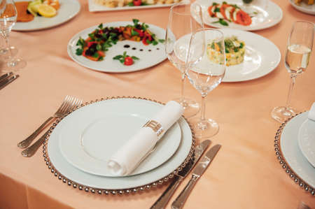 Luxurious restaurant. Luxurious interior, white tables, serving dishes and glasses for guestsの写真素材