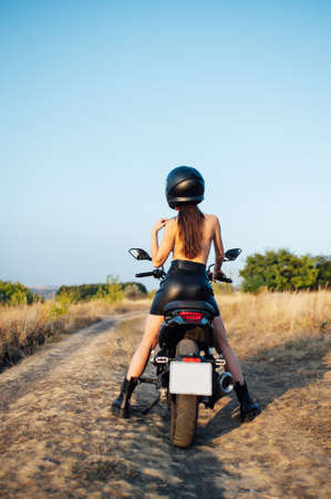 girl biker without underwear in a helmet sitting on a black motorcycleの写真素材