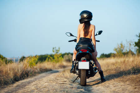 girl biker without underwear in a helmet sitting on a black motorcycleの写真素材