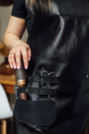 Person in black apron with professional hairdresser set on dark background, closeupの写真素材