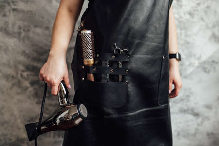 Person in black apron with professional hairdresser set on dark background, closeupの写真素材