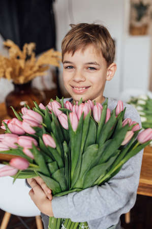 The boy smiles fervently with a bouquet of flowers