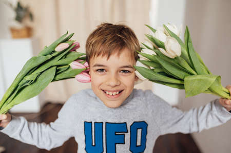 The boy smiles fervently with a bouquet of flowers