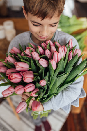 The boy smiles fervently with a bouquet of flowersの写真素材
