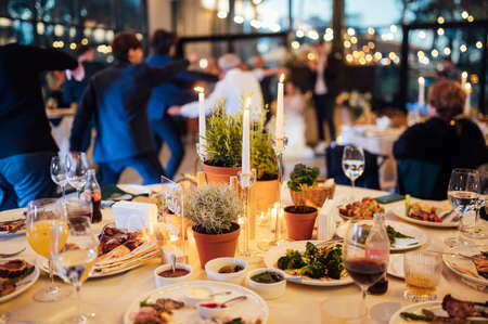 Flower and candle decoration for a wedding against the background of dancing guestsの写真素材