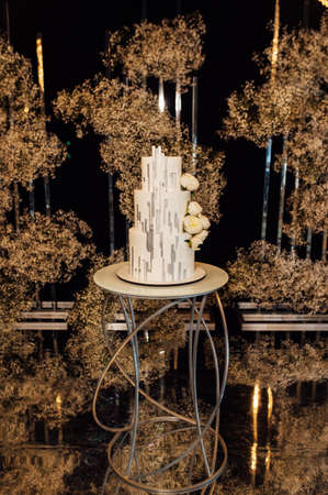 White-pink beautiful wedding cake on the background of the evening wedding archの写真素材