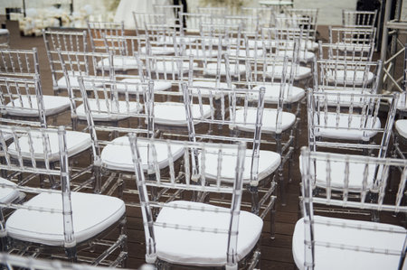 Glass chairs stand in a row in a beautiful wedding outing ceremonyの写真素材