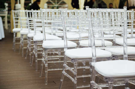 Glass chairs stand in a row in a beautiful wedding outing ceremonyの写真素材