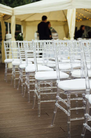 Glass chairs stand in a row in a beautiful wedding outing ceremonyの写真素材