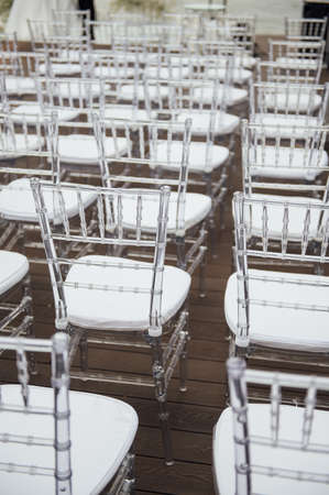 Glass chairs stand in a row in a beautiful wedding outing ceremonyの写真素材