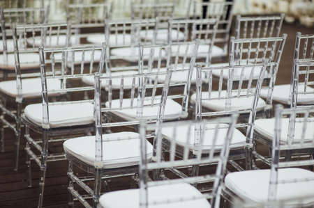 Glass chairs stand in a row in a beautiful wedding outing ceremonyの写真素材