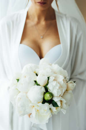 morning of the bride in the hotel room. slightly blurred image of a bouquet in the hands.の写真素材