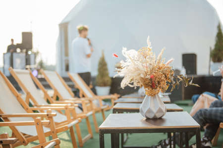 On the table is a decorative vase with dried flowers. Beautiful summer location for relaxationの写真素材