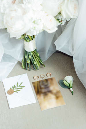 Wedding details flat lay. Wedding invitation and scroll paper. Bottle with fragrance. Simple bouquetの写真素材