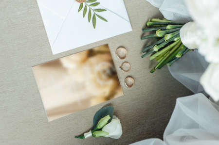Wedding details flat lay. Wedding invitation and scroll paper. Bottle with fragrance. Simple bouquetの写真素材