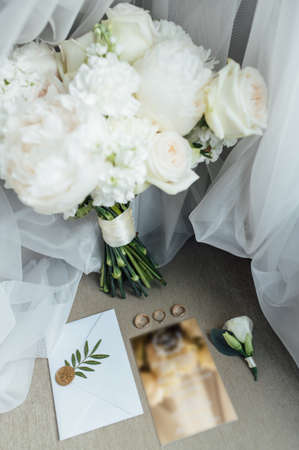Wedding details flat lay. Wedding invitation and scroll paper. Bottle with fragrance. Simple bouquetの写真素材