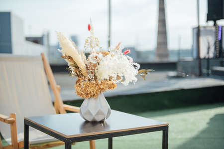 On the table is a decorative vase with dried flowers. Beautiful summer location for relaxationの写真素材