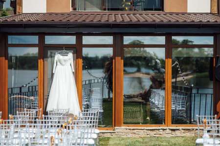 beautiful and elegant white wedding dress hanging on the glass facade of the buildingの写真素材