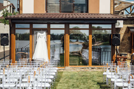 beautiful and elegant white wedding dress hanging on the glass facade of the buildingの写真素材