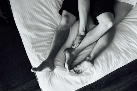 The feet of a young heterosexual couple relaxing in bed.の写真素材