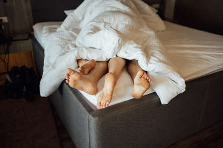 The feet of a young heterosexual couple relaxing in bed.の写真素材