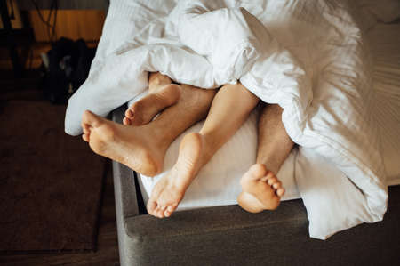 The feet of a young heterosexual couple relaxing in bed.の写真素材