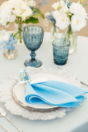 Wedding tables for guests with a blue tablecloth. Decorated with premium glasses and flowersの写真素材