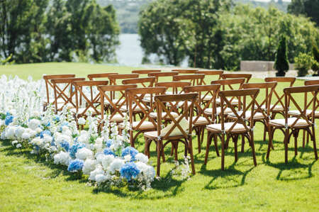 Incredibly beautiful outdoor ceremony on green grass and wooden chairs and fresh flowers. Wedding dayの写真素材