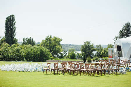 Incredibly beautiful outdoor ceremony on green grass and wooden chairs and fresh flowers. Wedding dayの写真素材