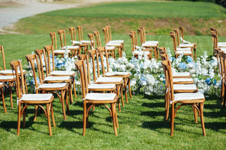 Incredibly beautiful outdoor ceremony on green grass and wooden chairs and fresh flowers. Wedding dayの写真素材