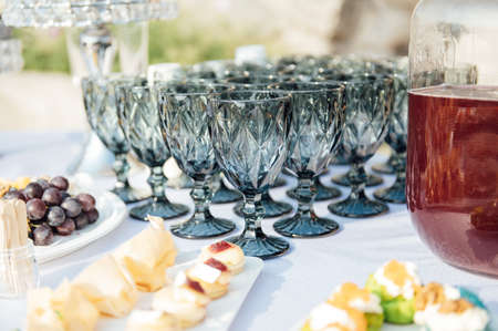 Elegant blue glasses without champagne stand in row next to canapes and snacks on picturesque background.の写真素材