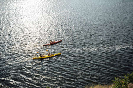 Two women and one man kayaking in the river at summer morning. Back viewの写真素材