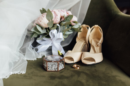 Wedding bouquet of white peonies, shoes and wedding rings on a wooden backgroundの写真素材