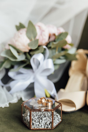 Wedding bouquet of white peonies, shoes and wedding rings on a wooden backgroundの写真素材