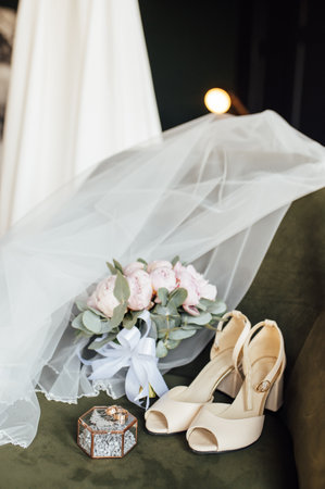 Wedding bouquet of white peonies, shoes and wedding rings on a wooden backgroundの写真素材