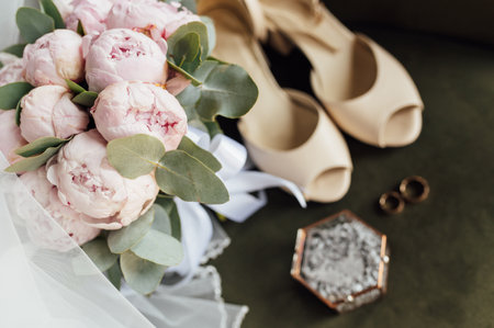 Wedding bouquet of white peonies, shoes and wedding rings on a wooden backgroundの写真素材