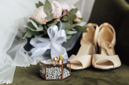 Wedding bouquet of white peonies, shoes and wedding rings on a wooden backgroundの写真素材