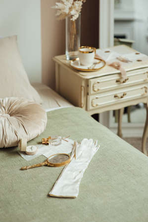 Vintage accessories on the bed and bedside table. Boho style. Gloves, cup and mirrorの写真素材