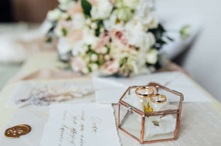 Beautiful wedding bouquet and rings of the newlyweds near the invitation cards. Boho style