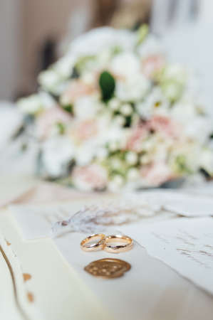 Beautiful wedding bouquet and rings of the newlyweds near the invitation cards. Boho styleの写真素材