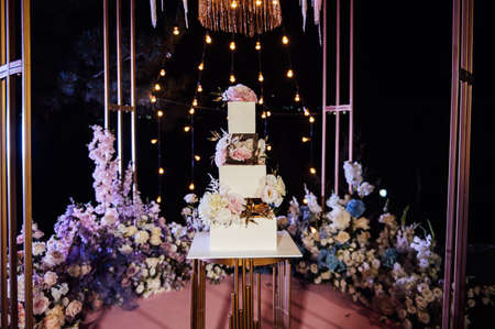Modern beautiful wedding arch with lots of flowers and a large wedding cake.の写真素材