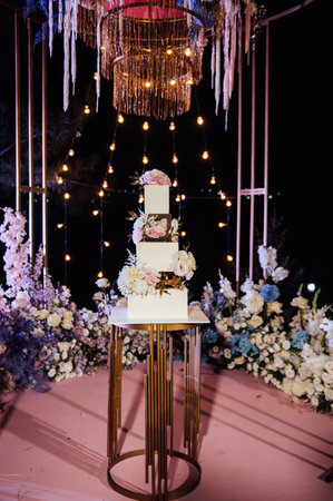 Modern beautiful wedding arch with lots of flowers and a large wedding cake.の写真素材