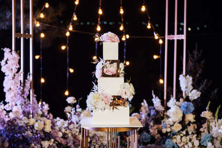 Modern beautiful wedding arch with lots of flowers and a large wedding cake.の写真素材
