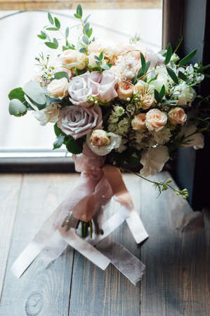 Wedding shoes with a bouquet standing on the floor. The shadow from the windowの写真素材