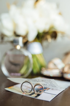 beautiful gold wedding rings on wooden table next to bouquet and shoesの写真素材