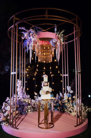 Modern beautiful wedding arch with lots of flowers and a large wedding cake.の写真素材